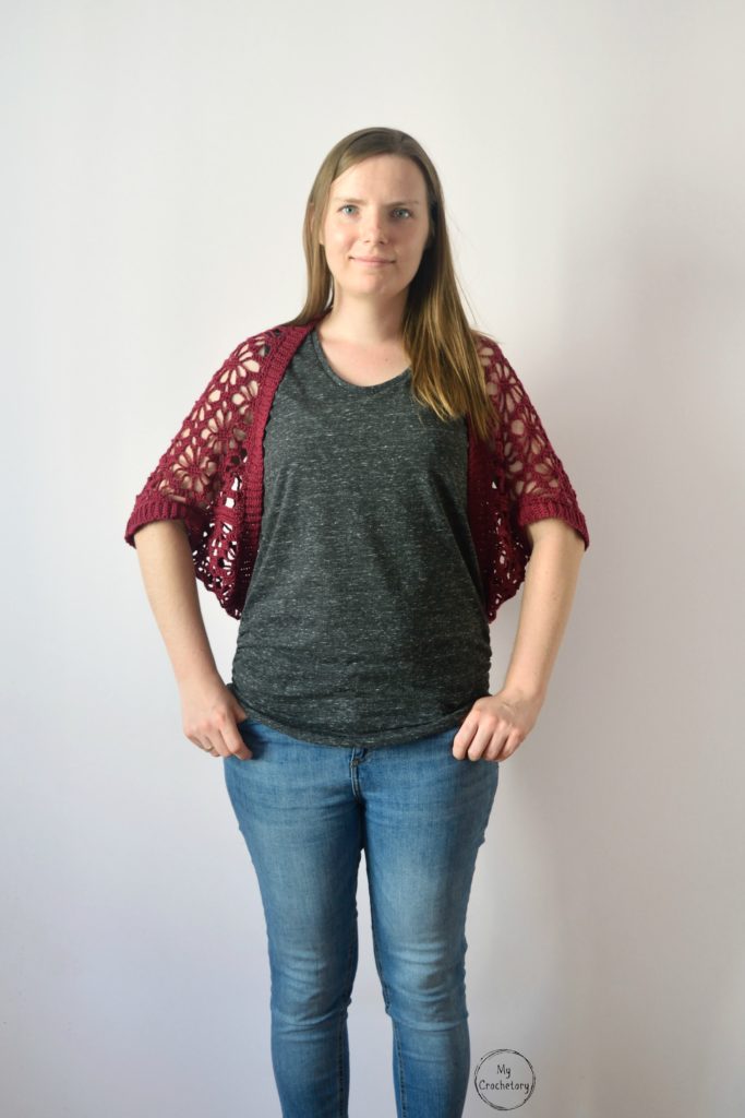 Front view of model showcasing a lace crochet shrug pattern in red.