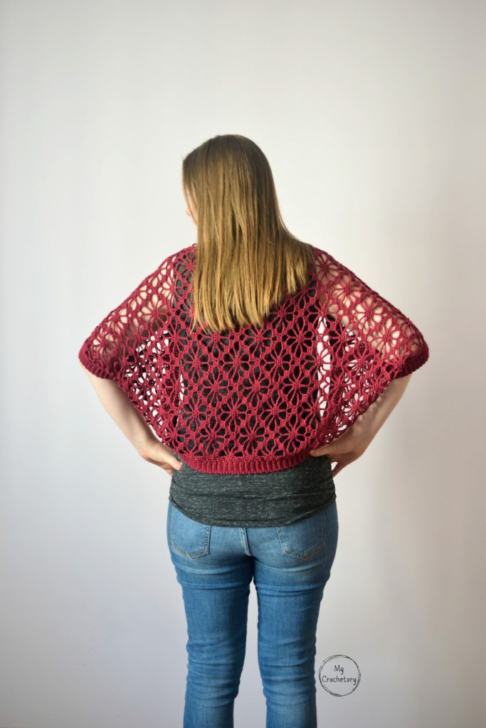 Back view of model wearing a crochet shrug pattern with floral lace design.