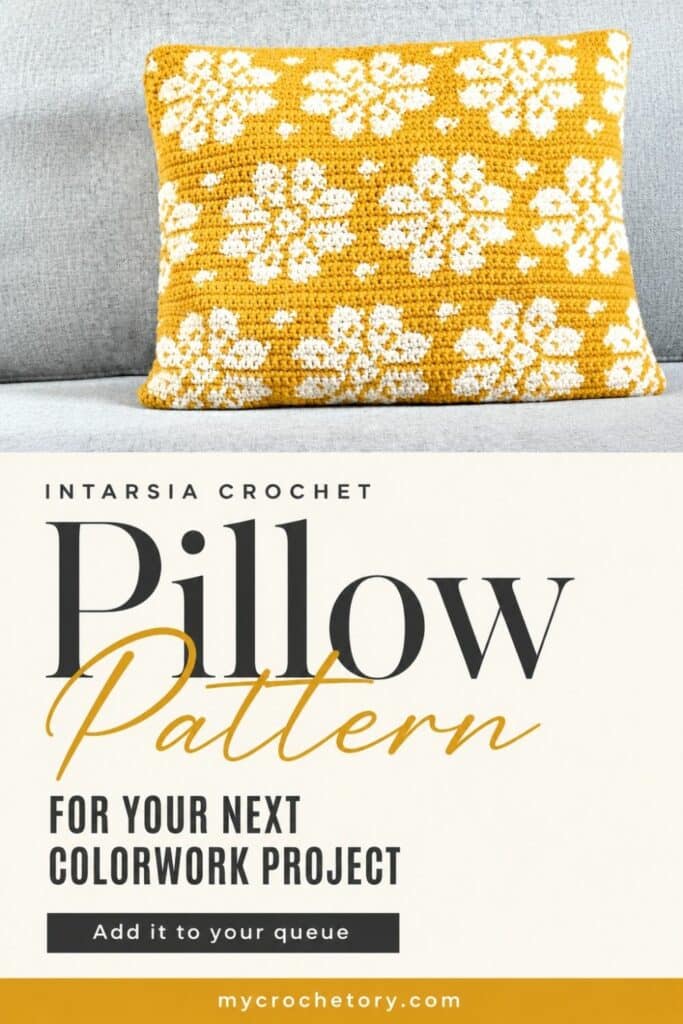 Mustard and white intarsia crochet pillow with dahlia flower design on a couch