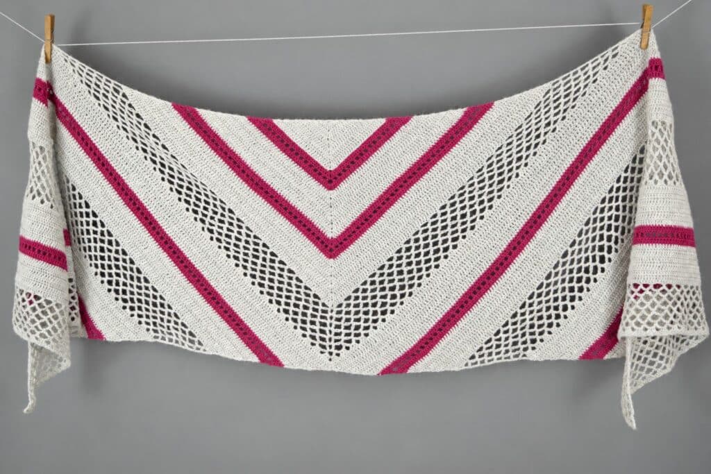 Finished trapezoid shawl crochet pattern hung flat, showing the full mesh lace and eyelet stripe design