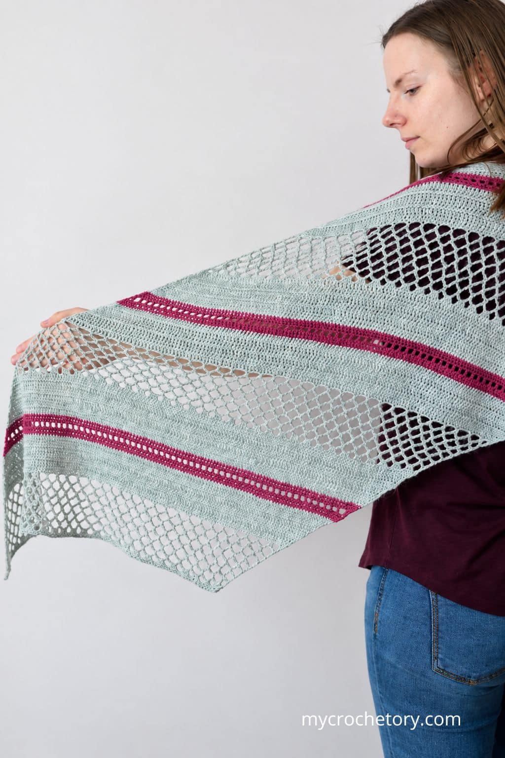 Woman holding the Spring Solstice Wrap open to show the shape of the crochet trapezoid shawl