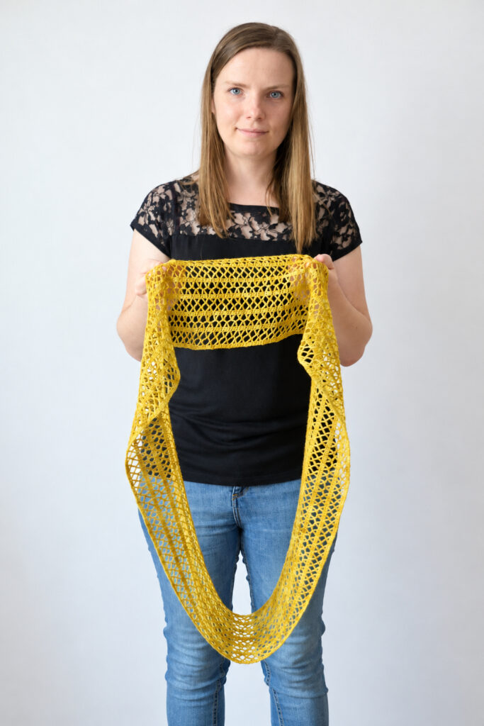 Woman holding the Sunny Lace Cowl open to show the full length of the crochet lace cowl