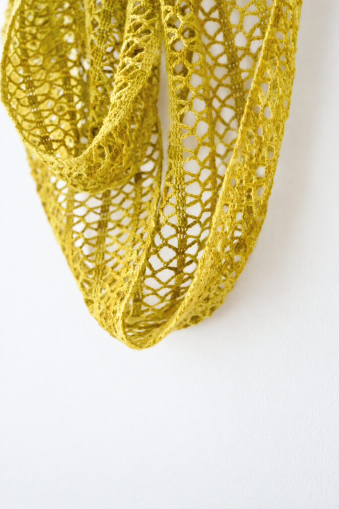 Close-up of the lace pattern on the Sunny Lace Cowl in ochre merino yarn