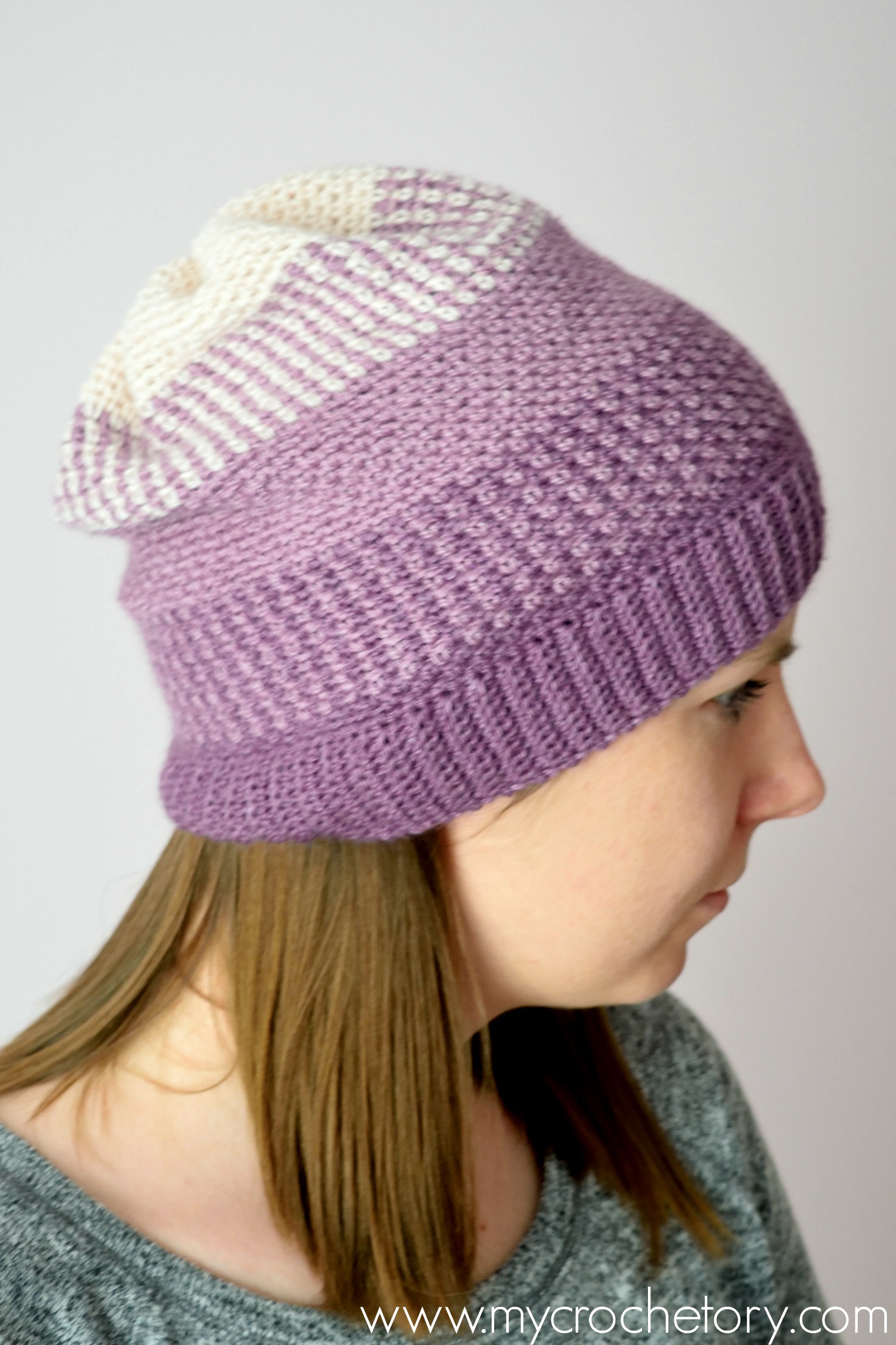 Moss stitch beanie seen from the side, with the purple brim and the slouchy cream top