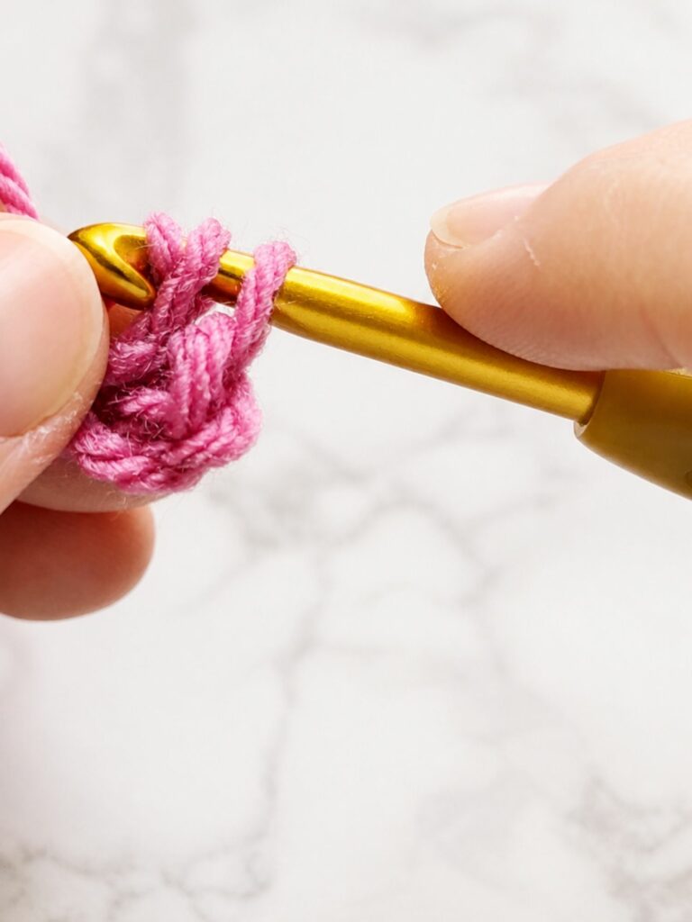 Pulling the last loop through the other two loops to complete a yarn over slip stitch crochet ribbing stitch