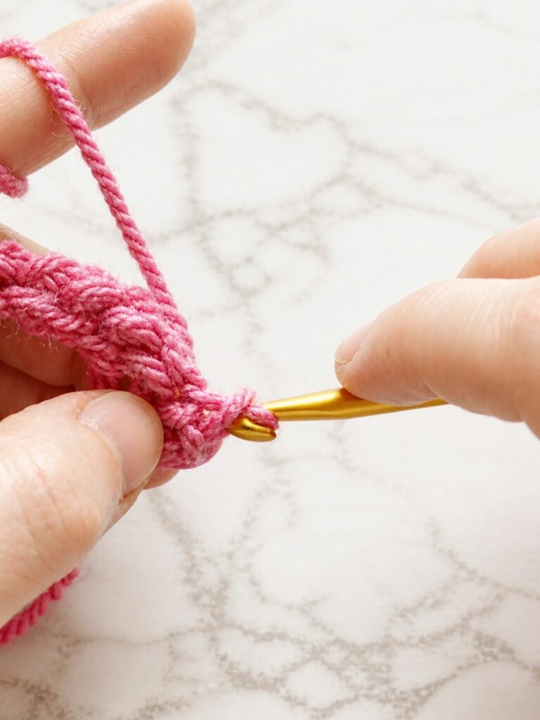 Close up of completing a yarn over slip stitch for crochet ribbing by pulling through the stitch and loop