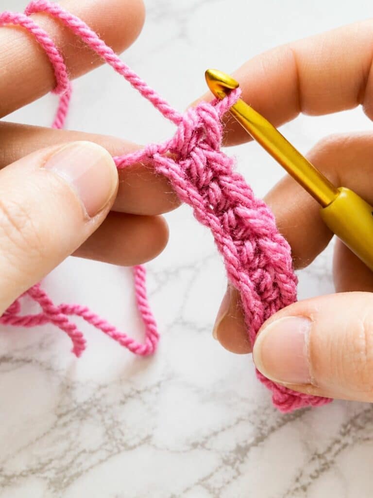 First row of back loop single crochet ribbing worked into the foundation chain with pink yarn