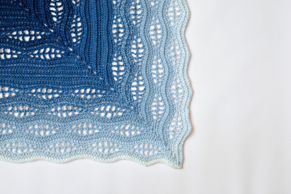 Close-up of a Kalinda Blanket corner with wavy light blue edges and lace holes