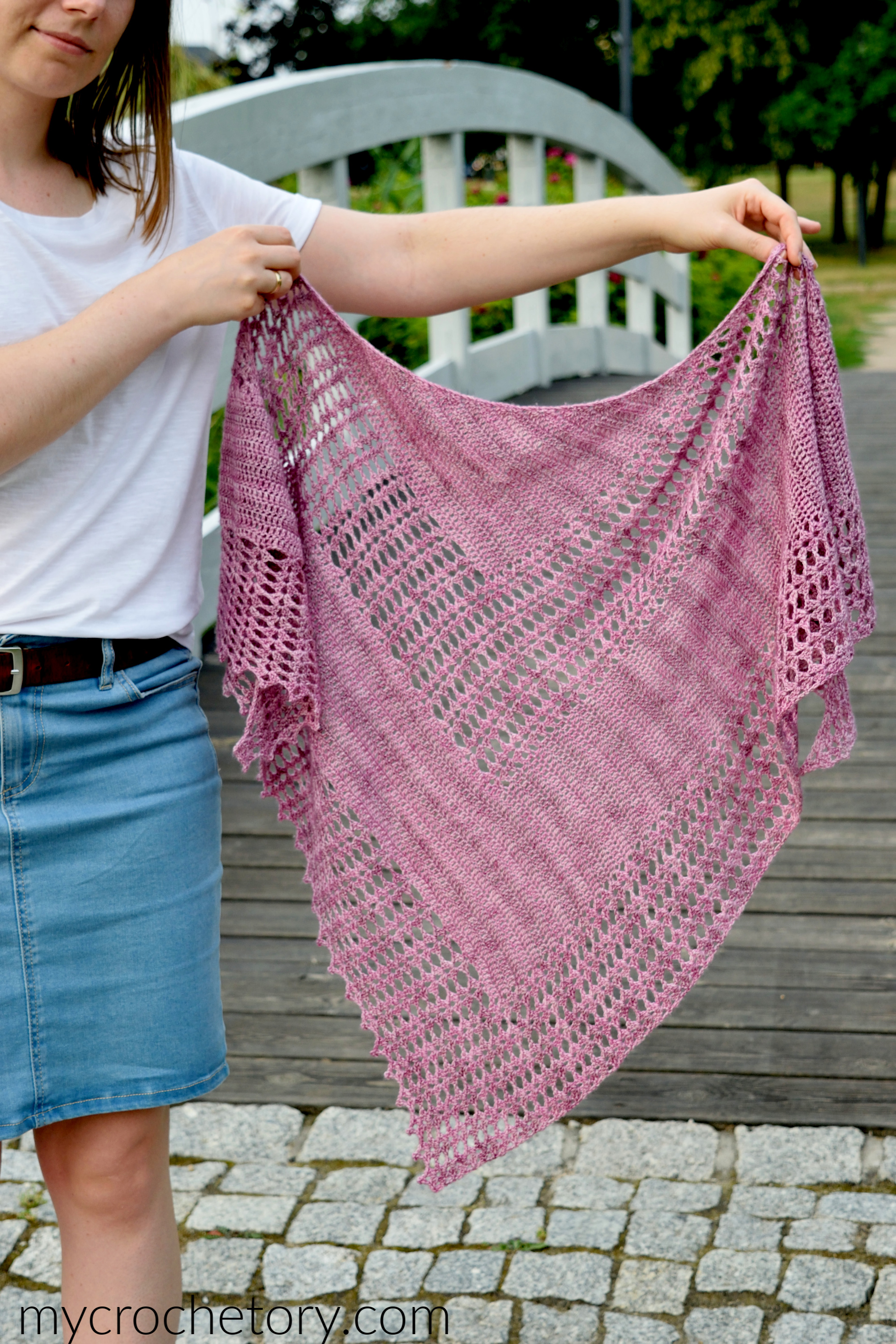 Despina lacy crochet shawl in pink fingering weight yarn draped over the shoulders