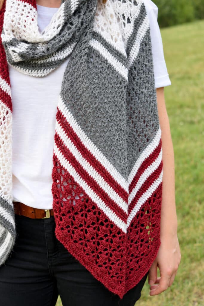 Close-up of the pointy end of the arrow crochet wrap with red fan lace and white, gray and red stripes