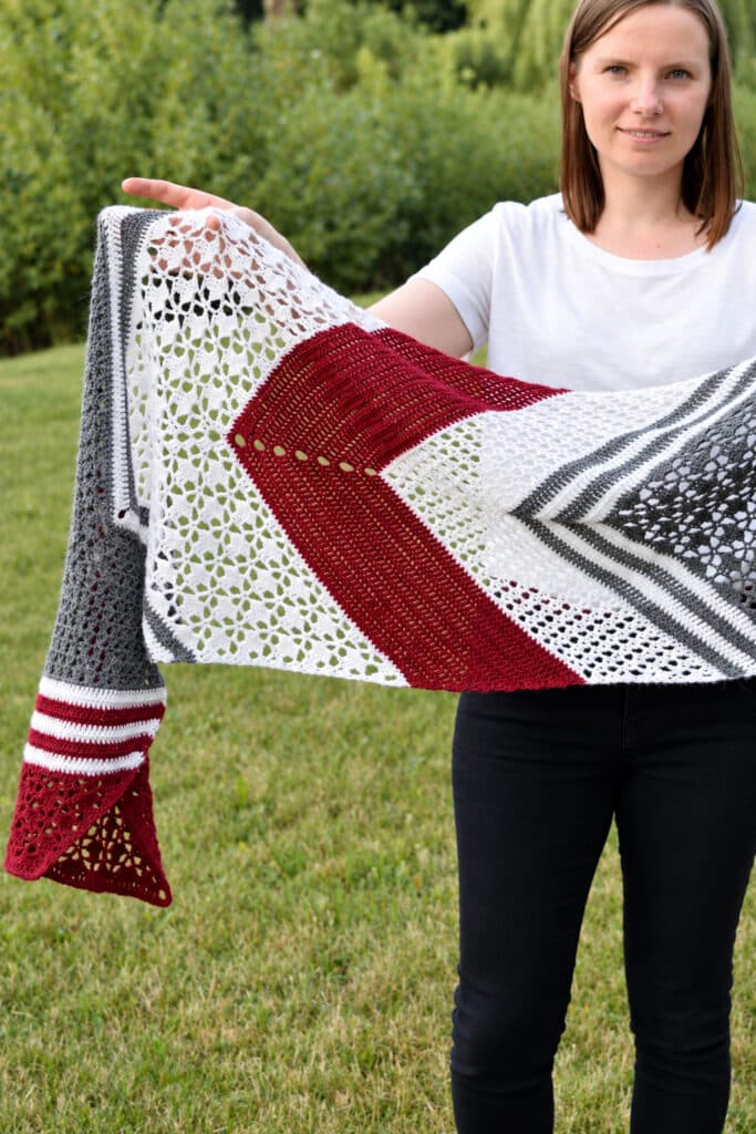 Long crochet wrap held out to the side to show the V-shaped stripes and the V end