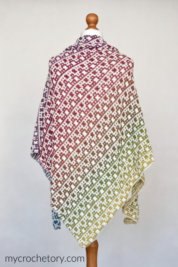 Crax Gradient Shawl in mosaic crochet on a mannequin, with pink, green and blue gradient stripes