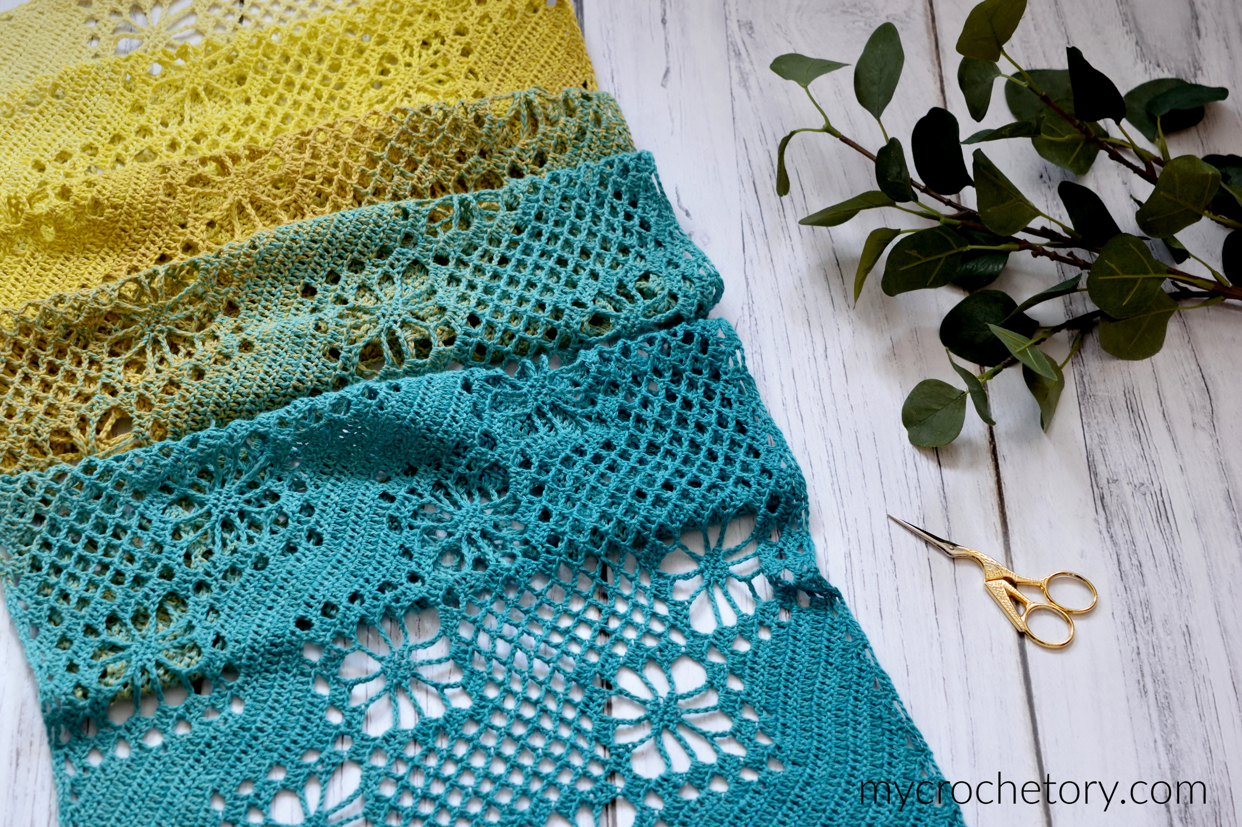 Corner to corner crochet scarf laid flat, with lace flower bands and mesh in yellow and teal
