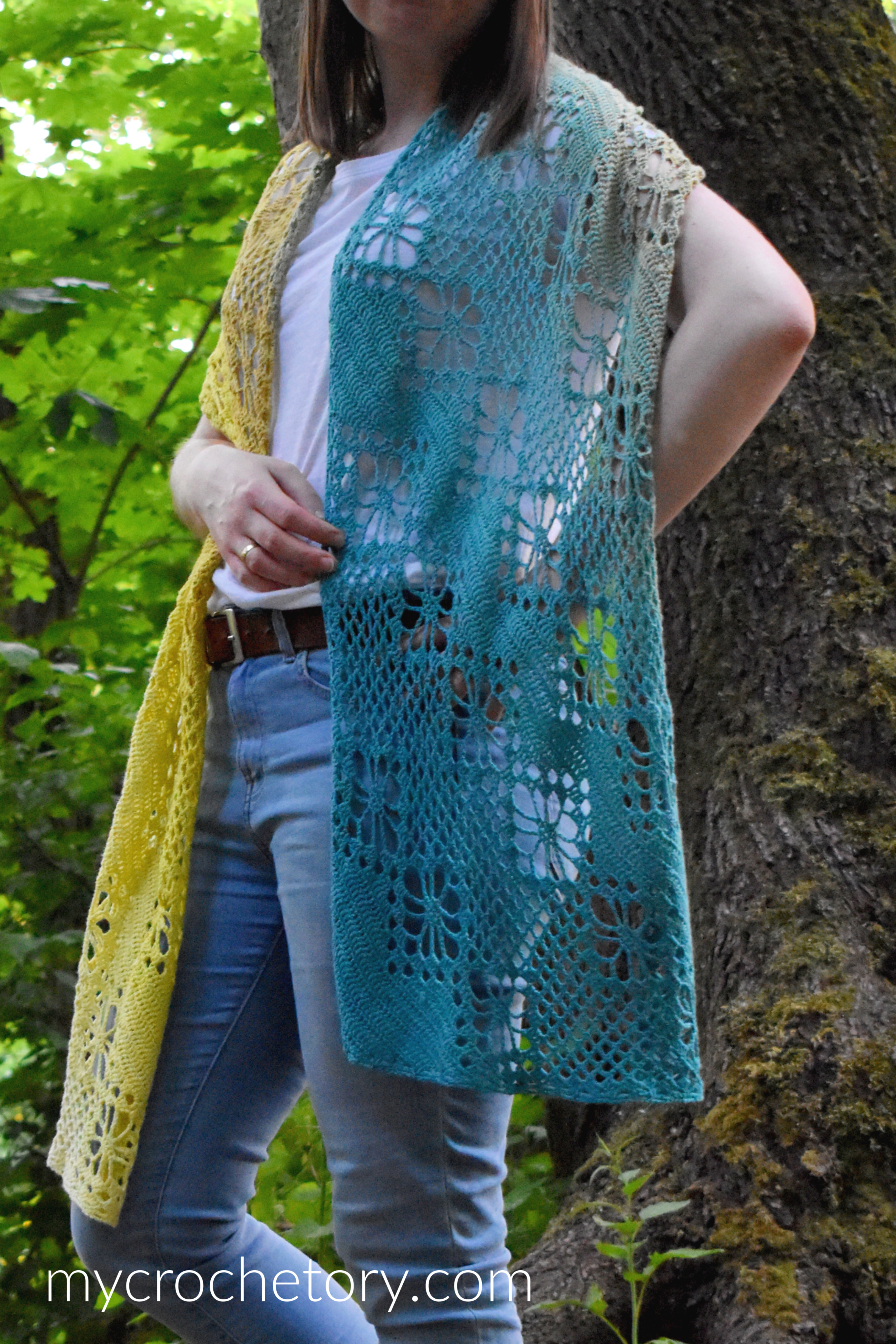 Teal end of the Zarina crochet scarf with lace flowers, worn next to a tree