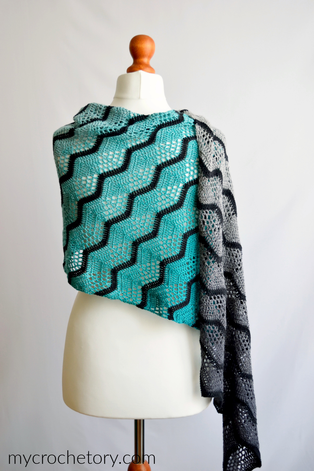 Havra ombre crochet wrap worn around the shoulders of a mannequin, turquoise side in front