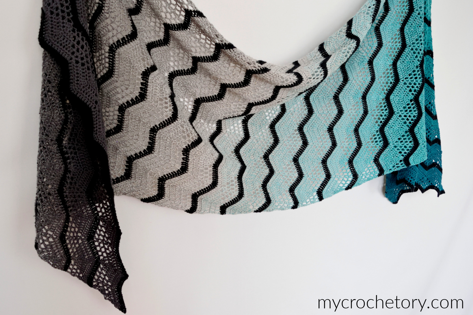 Havra Wrap held out flat, a long parallelogram with black chevrons on a gray and turquoise gradient