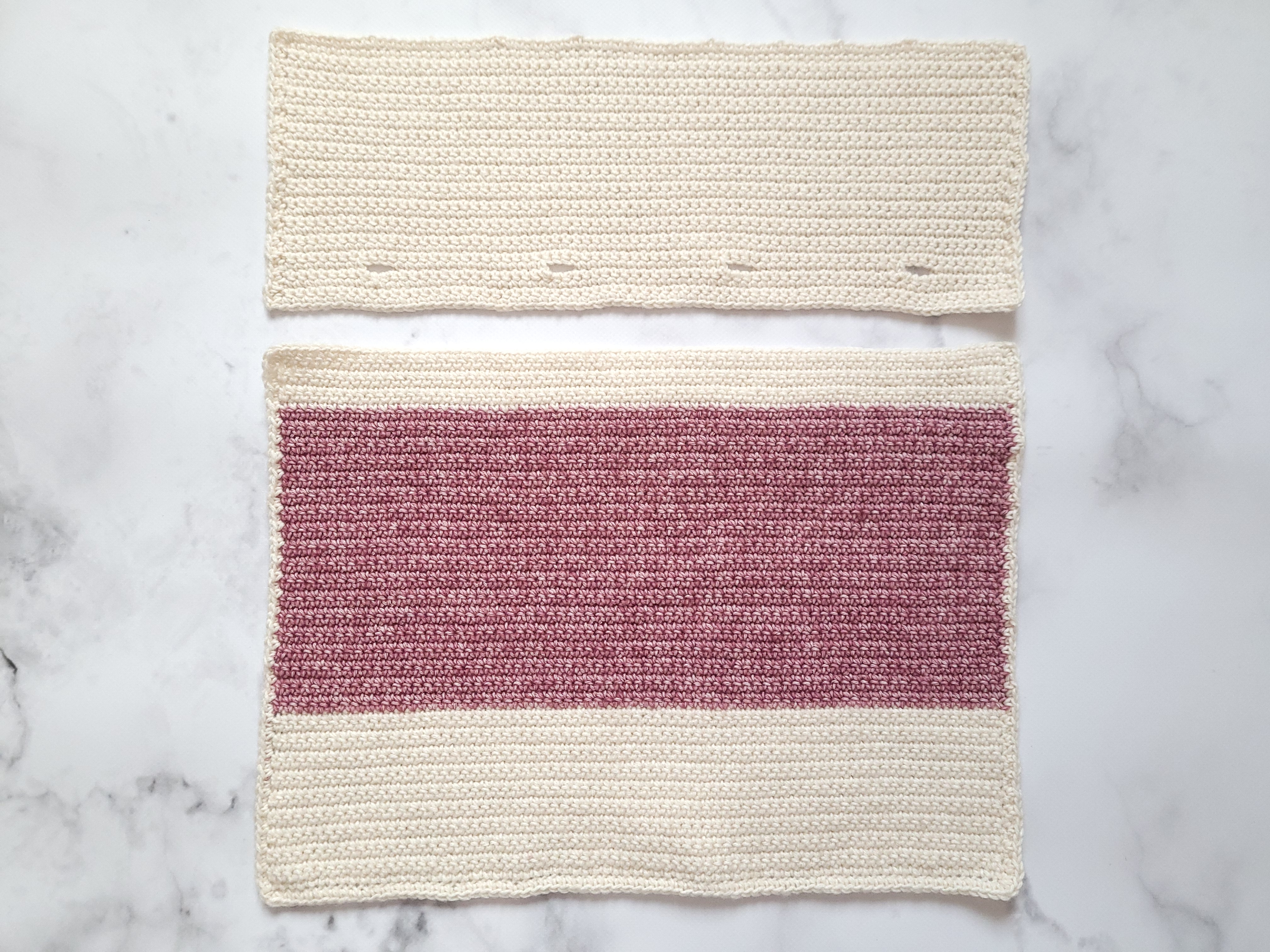 The two back pieces of the intarsia crochet pillow cover, the cream back top with buttonholes and the pink back bottom
