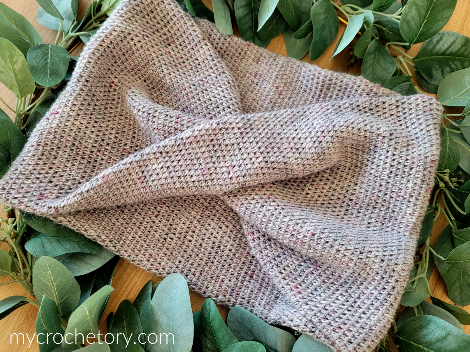 Lilac Mobius Cowl lying on green leaves