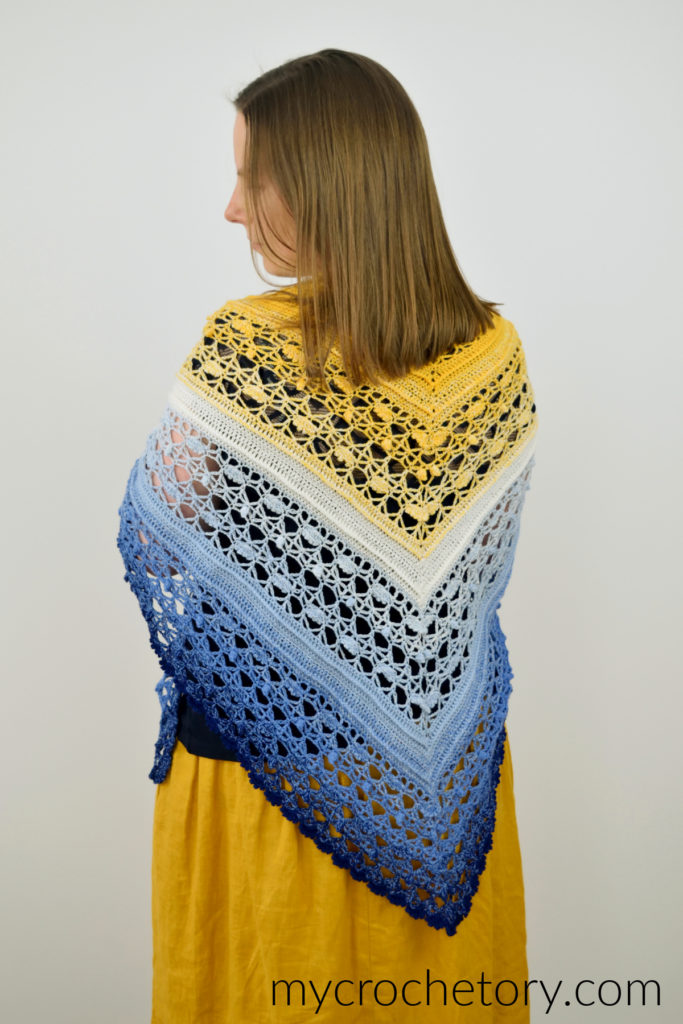 Avis crochet triangle shawl pattern worked in gradient yarn of fingering weight yarn.