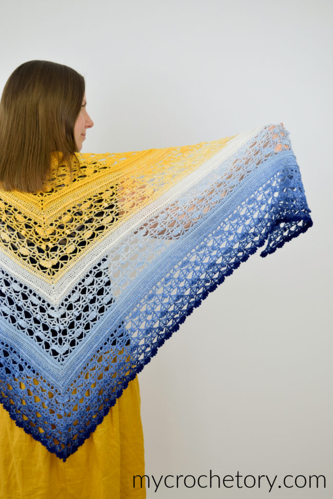 Avis crochet triangle shawl pattern worked in gradient yarn of fingering weight yarn.