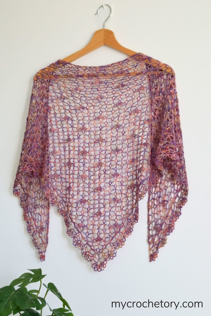 A close-up of a beautifully crafted lace crochet shawl, showcasing intricate stitches and delicate patterns, perfect for adding elegance to any outfit.