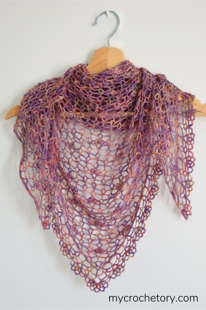 A close-up of a beautifully crafted lace crochet shawl, showcasing intricate stitches and delicate patterns, perfect for adding elegance to any outfit.