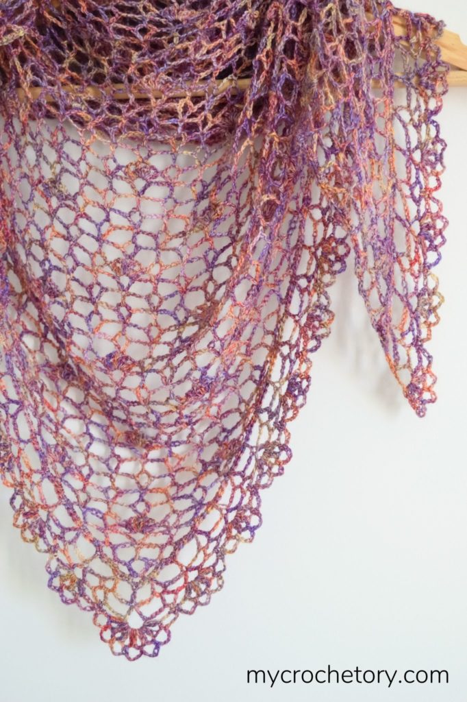A close-up of a beautifully crafted lace crochet shawl, showcasing intricate stitches and delicate patterns, perfect for adding elegance to any outfit.