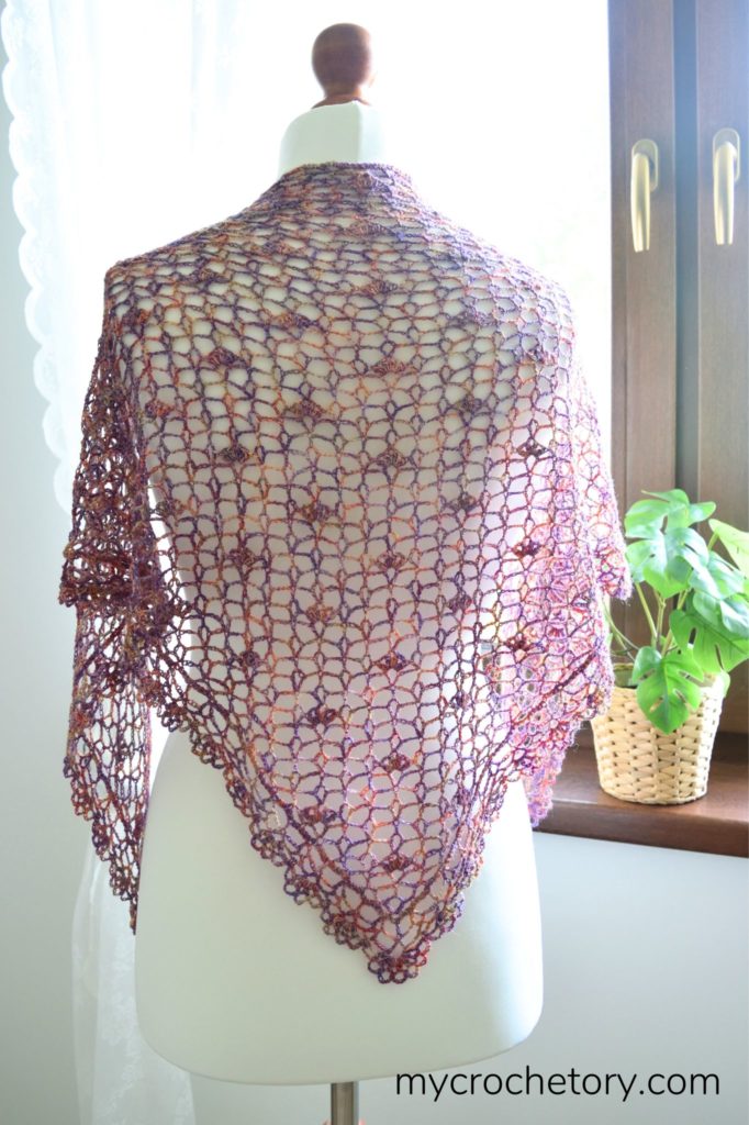 A close-up of a beautifully crafted lace crochet shawl, showcasing intricate stitches and delicate patterns, perfect for adding elegance to any outfit.