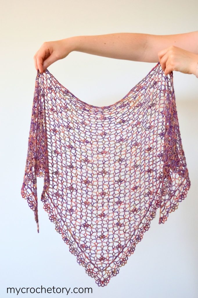 A close-up of a beautifully crafted lace crochet shawl, showcasing intricate stitches and delicate patterns, perfect for adding elegance to any outfit.