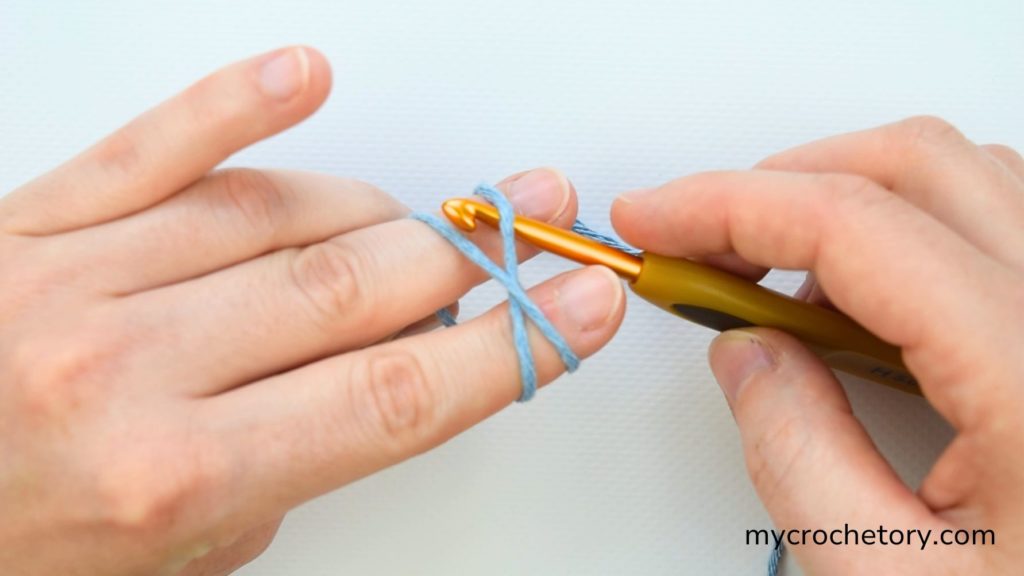 Close-up of how do I crochet magic circle with yarn properly crossed over fingers.