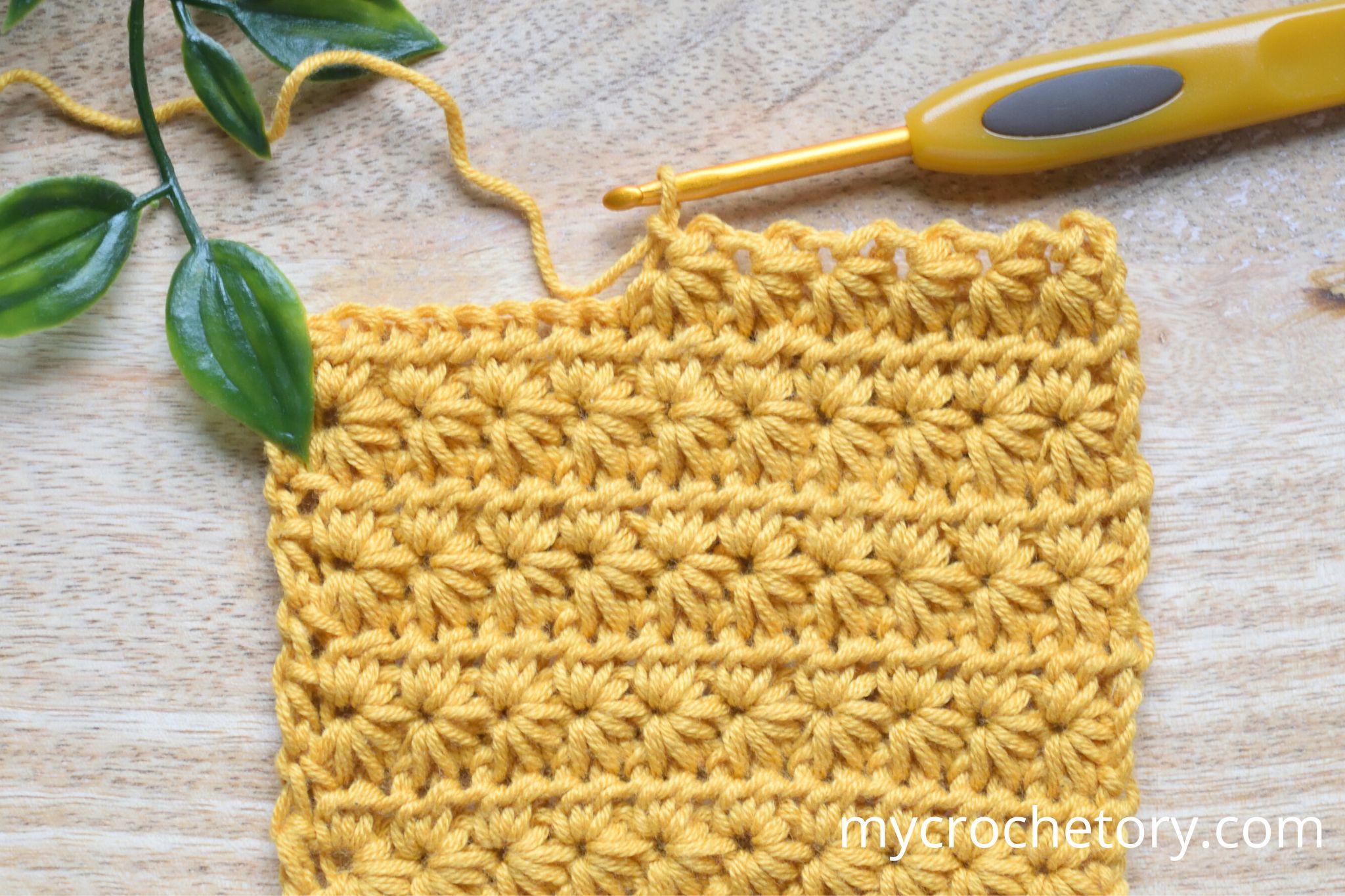 Mustard star stitch crochet swatch with a crochet hook