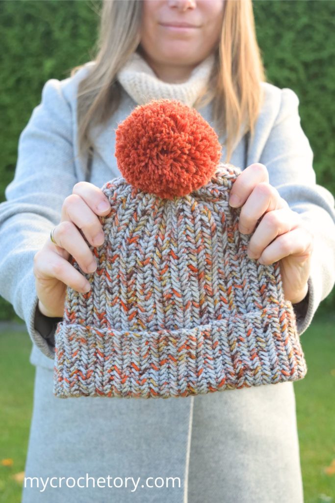 Model showcasing crochet winter hat pattern in the garden