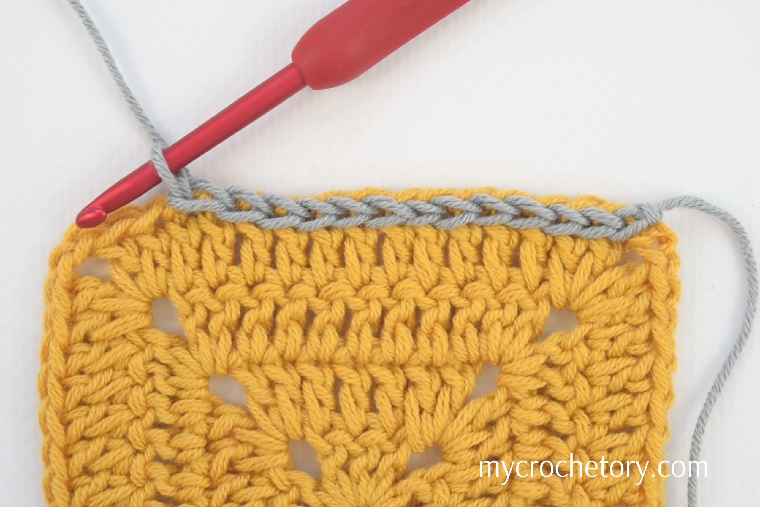 Slip stitches worked along the top of a yellow crochet swatch with a red hook