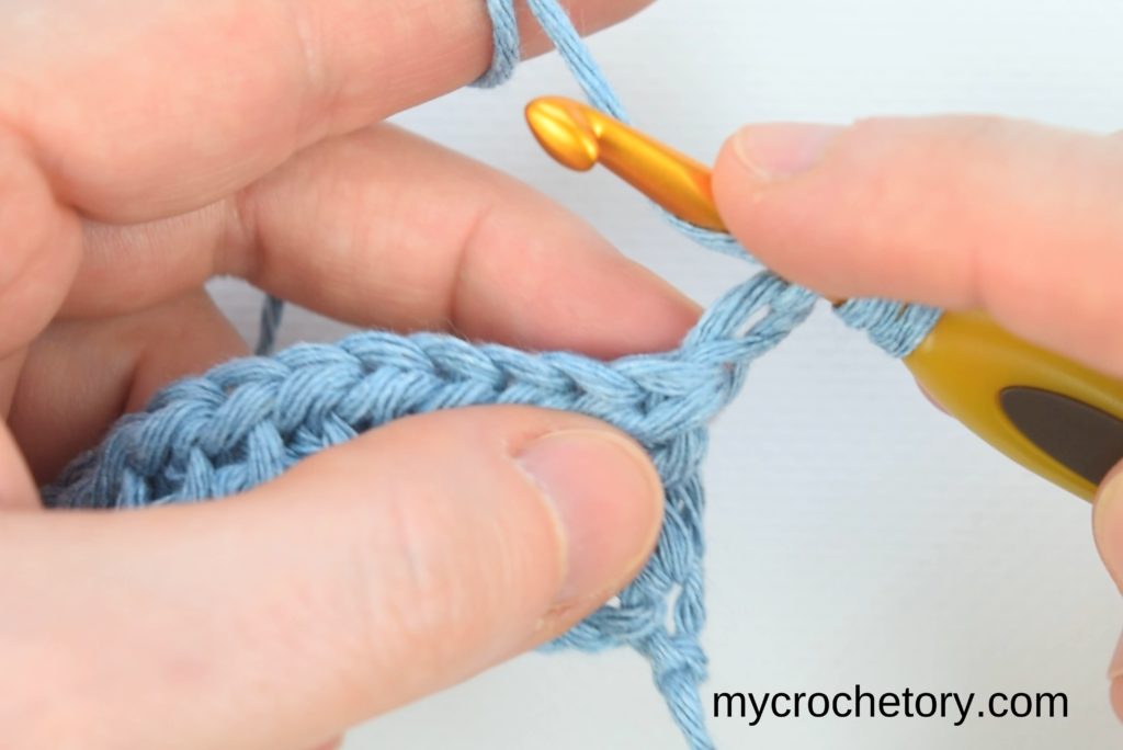 Detailing the yarn-over process and hook insertion into the first stitch, emphasizing going under both top loops.