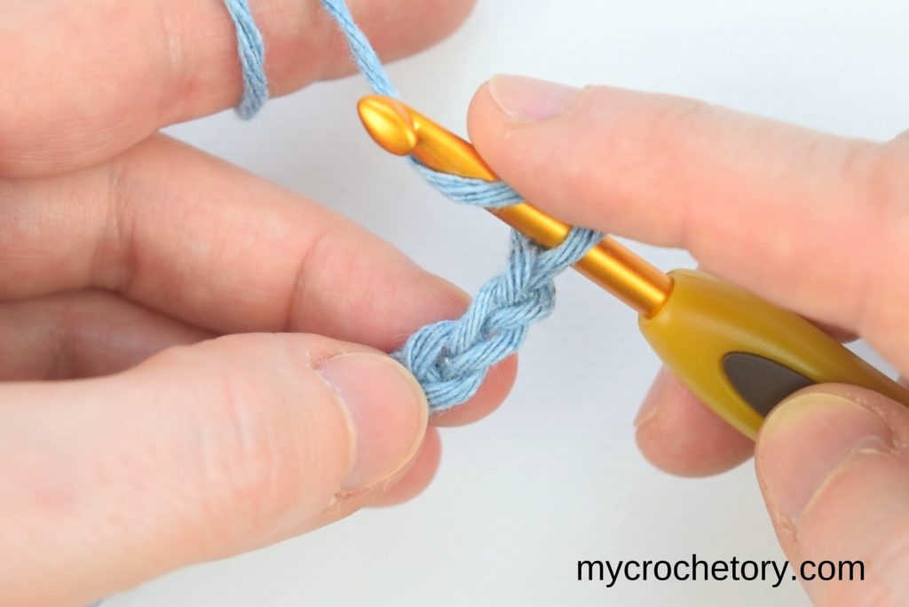 Demonstrating the yarn-over technique and hook insertion into the third chain from the hook.