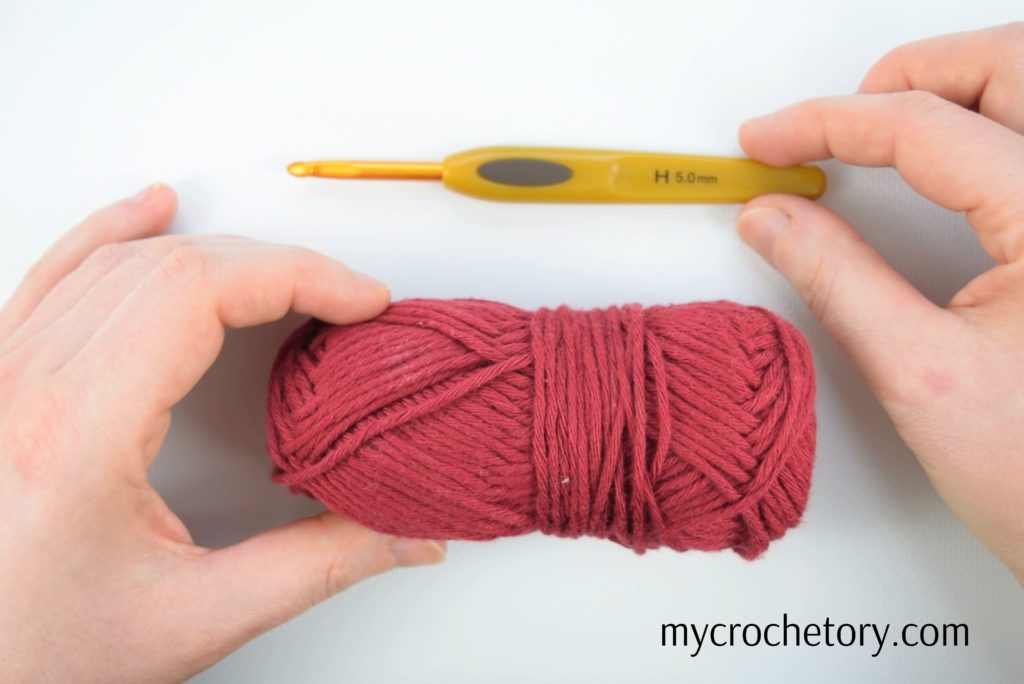 Hands holding crochet hook and yarn skein - illustrating 'how to crochet a chain' in a beginner-friendly tutorial.
