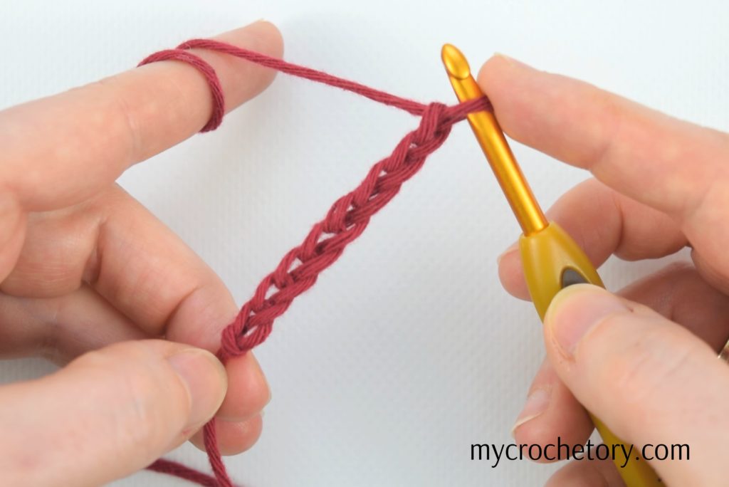 Hands demonstrating 'how to crochet a chain' with neatly worked chains – a visual guide for beginners.