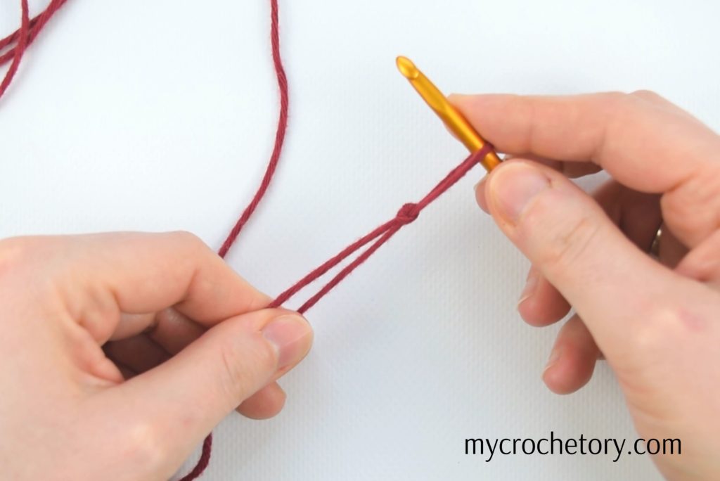 Hands creating a slip knot – the first step in crocheting a chain. Learn how to crochet a chain with our easy guide!