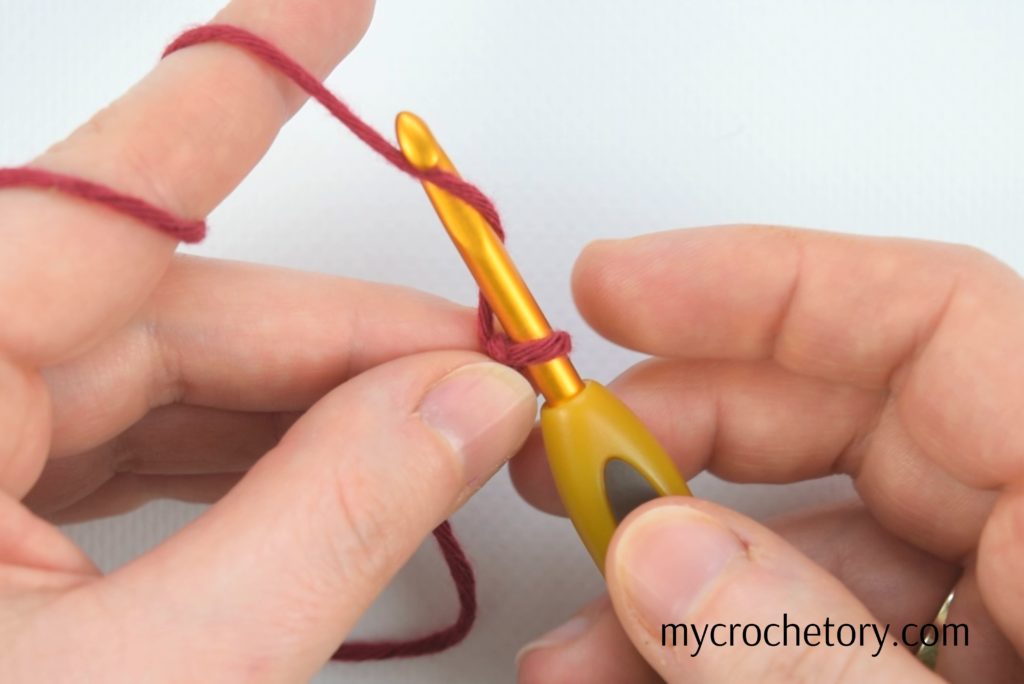 Crocheting a chain tutorial – hands performing yarn over technique for a seamless start. Master the art with our 'How to Crochet a Chain' guide!