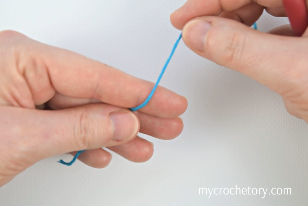 Yarn tail and working yarn draped over left hand, creating a slip knot for crochet.