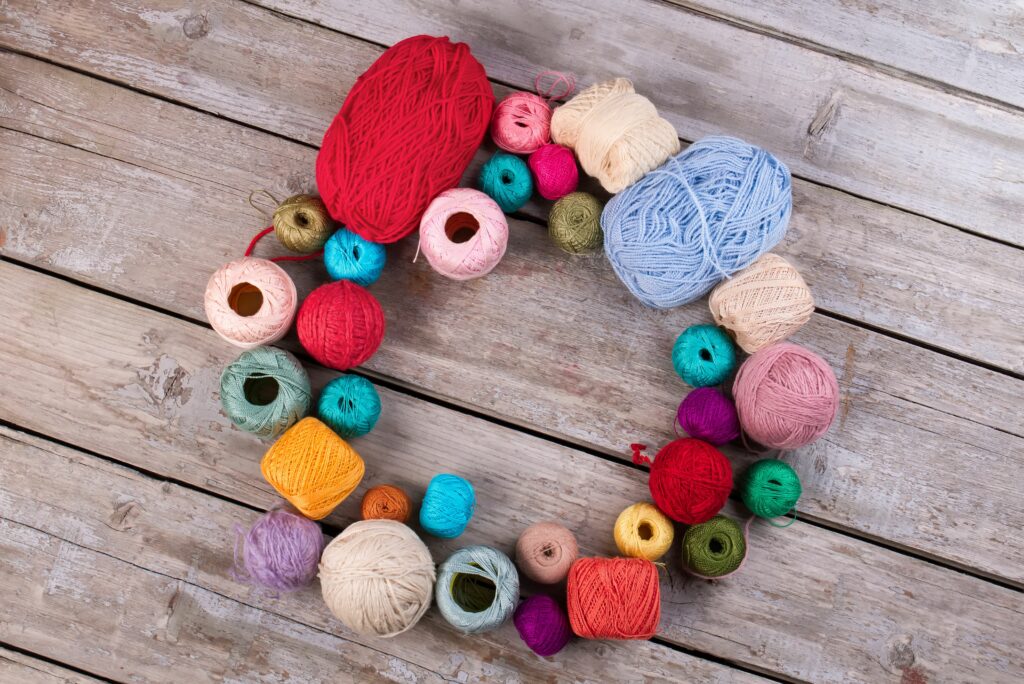 Colorful yarn skeins arranged on table, comparing crochet vs knitting yarn types.