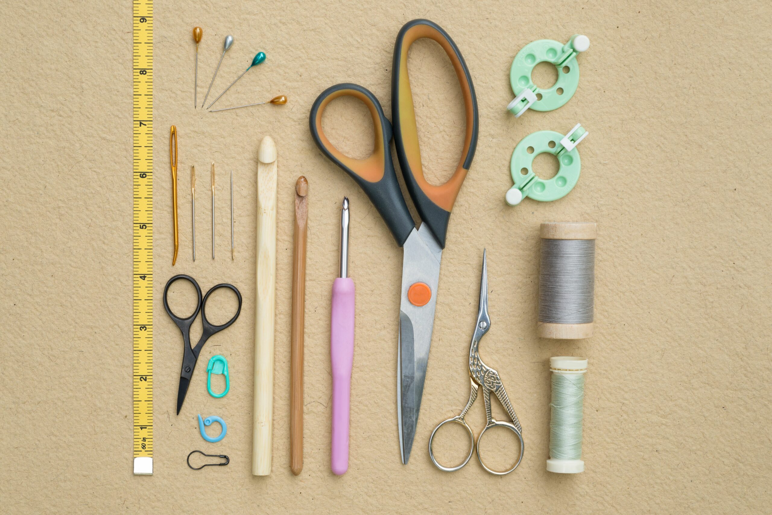 Crochet hooks, scissors, stitch markers, pins and a tape measure laid out on a white table