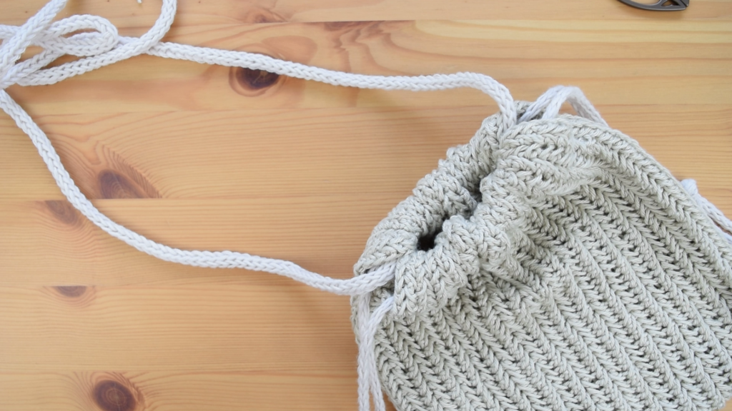 Completed crochet drawstring bag pattern lying flat with drawstrings