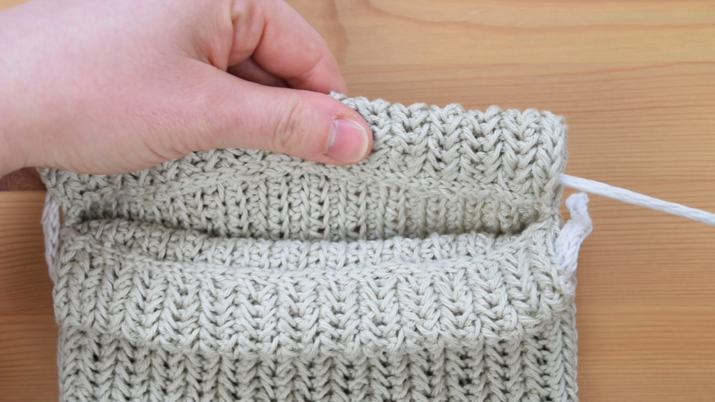 Close-up of threading I-cord in crochet drawstring bag pattern