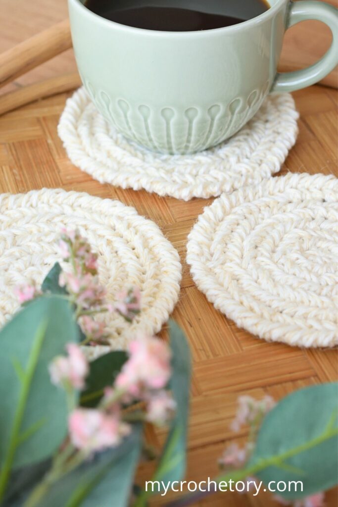 Cup of coffee on a beautifully crafted round crochet coaster pattern with herringbone stitches.