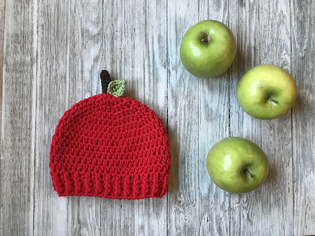 A vibrant red crochet hat designed to look like an apple, featuring fun infant crochet hat patterns for kids.