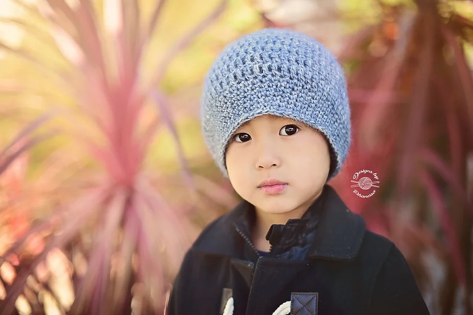 A child modeling a soft blue crochet hat, part of versatile infant crochet hat patterns for warm outfits.