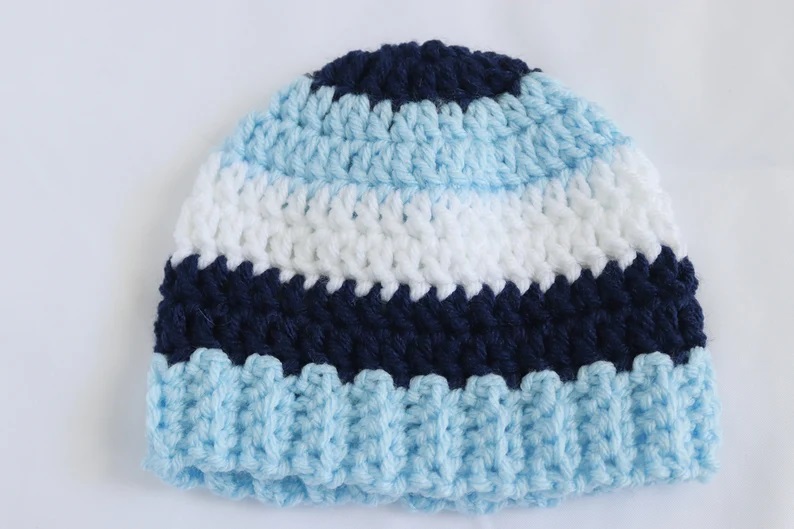A cozy blue and white striped infant crochet hat featuring a ribbed brim, perfect for little ones in various infant crochet hat patterns.