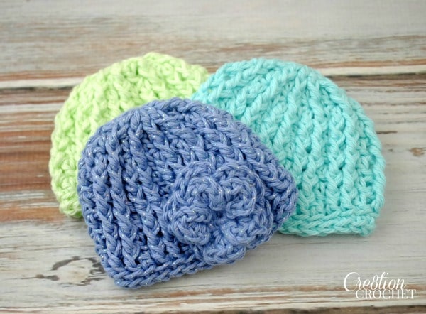 Three colorful infant crochet hats, featuring a blue hat with a flower, perfect for your infant crochet hat patterns collection.