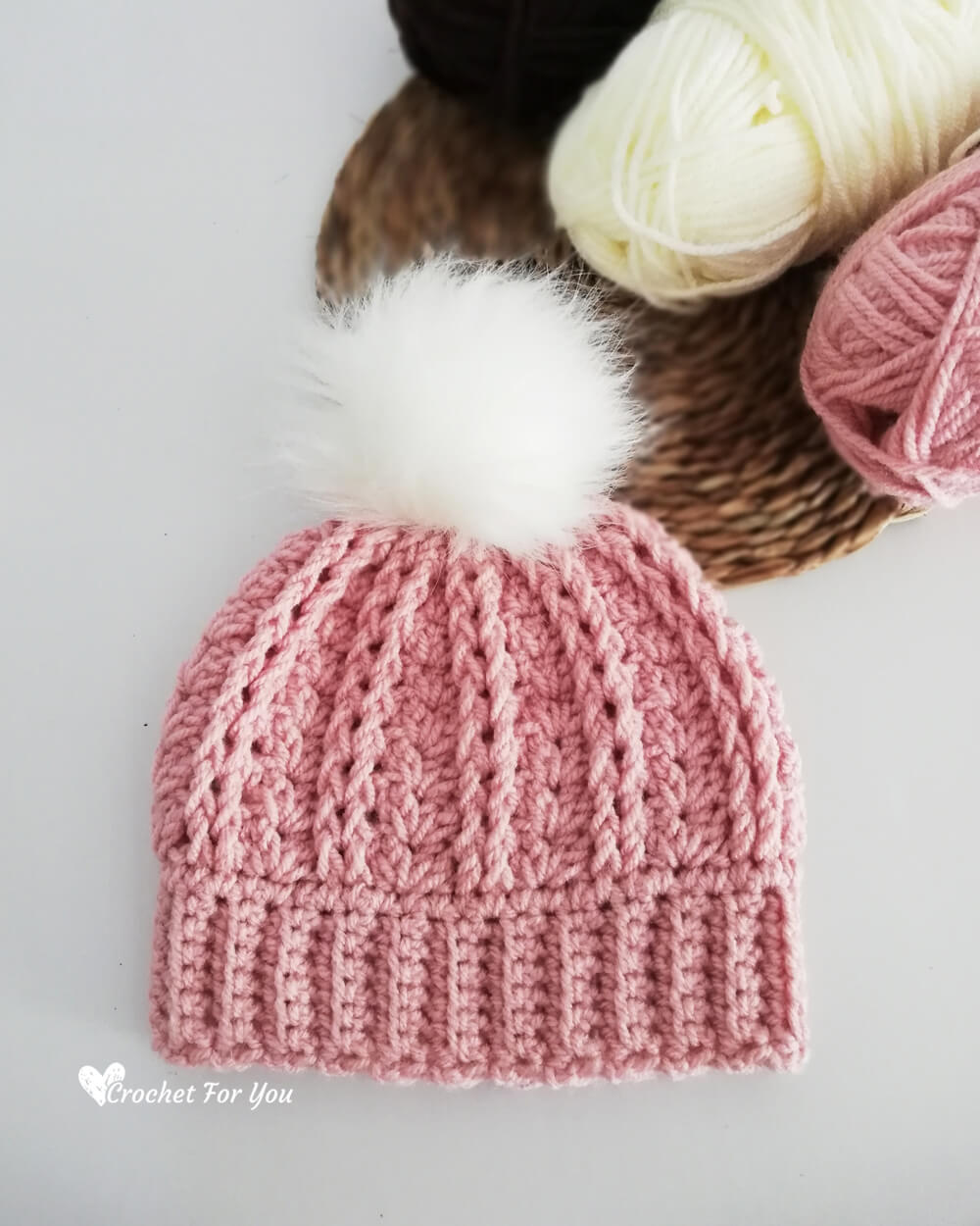 A stylish pom-pom beanie for infants with a soft pink color, perfect for chilly days.